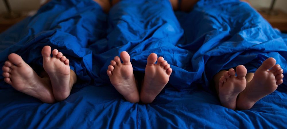 three people in bed in a polyamourous relationship Chicago